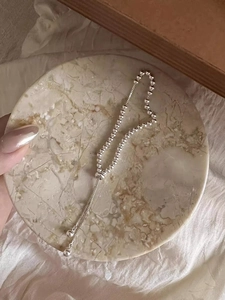 Dettaglio di un bracciale a sfere d'argento regolabile su vassoio di marmo e pizzo