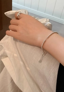 Primo piano del bracciale regolabile con perline argentate e anello a nodo