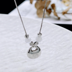 Close-up of a silver Ruyi lock pendant with Fu character and white bead accents