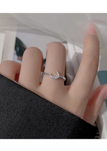 Macro shot of a minimalist moon ring with inlaid white zircons on a silver band