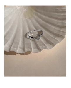 Macro shot of silver moon ring with sparkling crystals on white seashell background