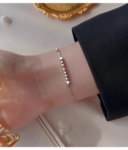 Détail d'un bracelet minimaliste à perles et cœurs porté au poignet pour femme
