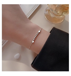Gros plan d'un bracelet en perles de cœur argenté porté par un mannequin en milieu pro