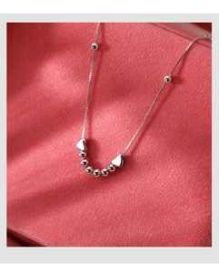 Gros plan détaillé d'un bracelet chaîne box argenté avec breloques cœur et perles polies