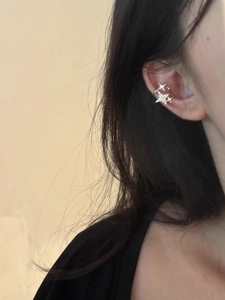 Detail showing two silver stars ear cuff with crystals worn on a woman's ear cartilage