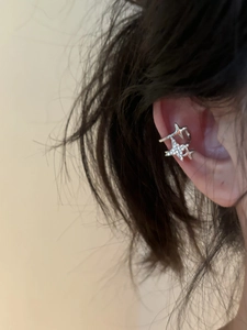 Detail of silver star ear cuff with sparkling zircon inlay worn on a model's ear