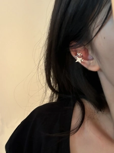 Detail of silver star ear cuff with zircon crystals worn by a model on the ear cartilage