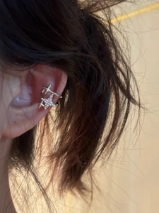Detailed close-up of a silver star ear cuff with pavé crystals worn on a model's ear