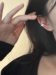 Close-up of star shaped rhinestone ear cuff worn on earlobe with shiny silver finish