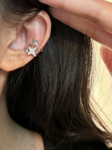 Macro view of a silver star-shaped ear cuff featuring sparkling micro-pave crystals on the ear