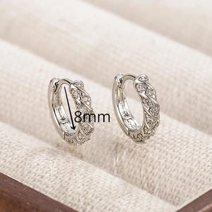 Macro shot of 8mm twisted silver huggie earrings with pavé zircons in a jewelry box