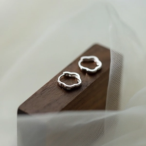 Detail shot of silver S925 hallmark on wavy polished high-shine sterling silver hoop earrings