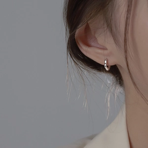 Detail of silver wavy hoop earrings with minimalist texture on model's ear