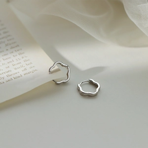 Close-up of S925 sterling silver wavy flower hoop earrings on a soft tulle background
