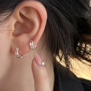 Close-up of silver lava texture hoop earrings showing liquid metal design on ear lobe