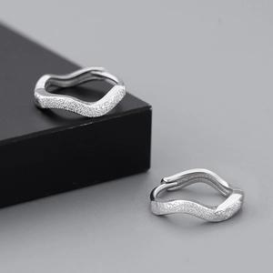 Detailed view of silver wave-shaped earrings with textured frosted and polished finish
