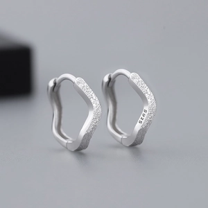 Macro shot of S925 sterling silver stamp on polished wavy textured hoop earrings