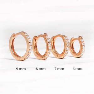 Rose gold earrings in four sizes 6mm to 9mm with micro-pave crystals on marble surface