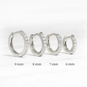 Set of four silver rhinestone hoop earrings in sizes 6mm, 7mm, 8mm, and 9mm on marble