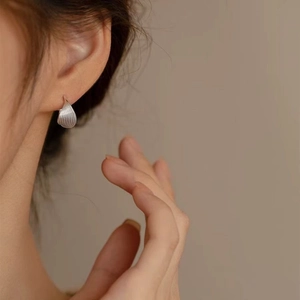 Detail of silver drop earrings with pleated texture and sterling silver hook for women
