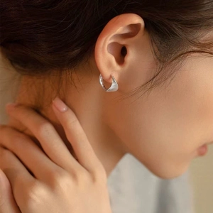 Macro shot of silver hoop earrings with spiral texture shown on a female model