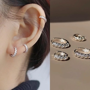Macro detail of twisted silver hoop earrings with micro-pave cubic zirconia inlay
