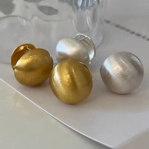 Matte gold and silver dome stud earrings with brushed finish on a clean white surface