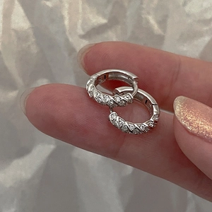 Detailed view of silver braided huggie earrings with micro-pave cubic zirconia stones