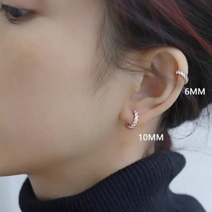 Macro detail of 6mm and 10mm rose gold zircon earrings set on a model ear