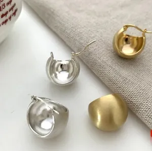 Macro view of dome hoop earrings featuring matte gold and polished silver finishes