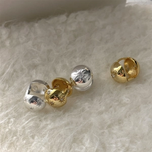 Detailed view of silver and gold starburst earrings with sparkling zircon on faux fur