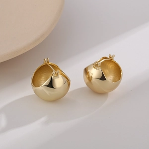 Detailed view of polished gold spherical earrings with a smooth mirror finish and secure clasp