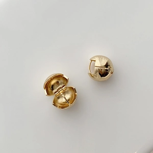Detailed view of gold minimalist huggie earrings with polished mirror spherical design