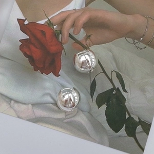 Polished silver spherical earrings held with a red rose for a vintage aesthetic style