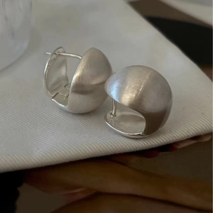 Macro detail of 925 sterling silver hemispherical hoop earrings with matte brushed finish