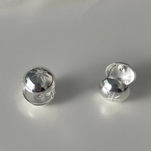 Detailed view of spherical silver earrings with starburst engraving and central crystal