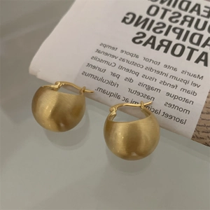 Detailed macro view of matte gold rounded hoop earrings with a brushed metallic texture finish