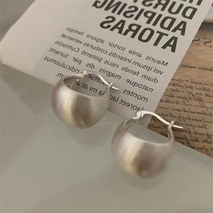 Detailed close-up of matte silver thick hoop earrings with brushed metal texture finish