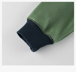 Detail shot of green knit sweater with navy blue ribbed cuffs and fine stitching