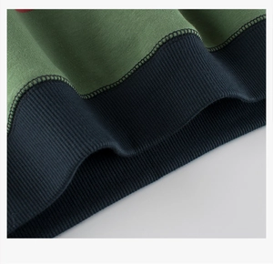Detailed close-up of green fleece hoodie fabric with navy ribbed cuffs and durable stitching