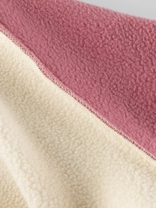 Close-up of thick pink and cream fleece fabric with soft texture and stitching detail