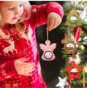 Kid holding wooden angel bell ornament near decorated Christmas tree with starry lights