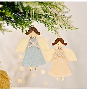 Détail d'ornements d'anges de Noël en bois avec ailes en feutre sur sapin enneigé