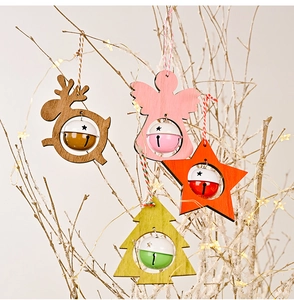 Detailed view of wood Christmas ornaments with bells on a snow-covered branch