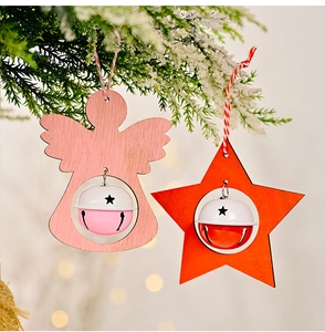 Close-up of wooden angel and star ornaments with metal bells hanging on a pine tree