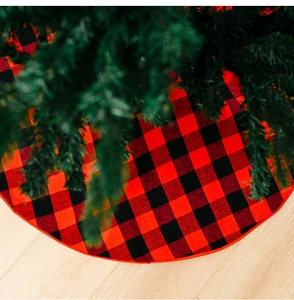 Detail of red and black buffalo plaid Christmas tree skirt on light wooden floor