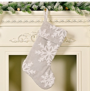 Close-up of gray plush Christmas stocking with white snowflake on fireplace background