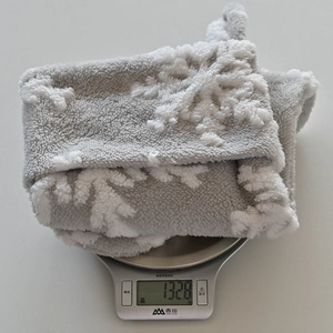 Detailed view of large plush snowflake Christmas stocking weighing 132.8g on a digital scale