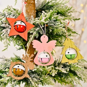 Wooden Christmas ornaments with colorful bells hanging on a snowy evergreen tree branch