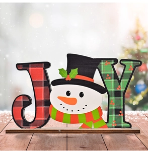 Close-up of JOY wooden Christmas table sign with snowman and festive plaid patterns